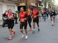 Corredores alegres participan en una media maratón, con dorsales visibles. El ambiente festivo sugiere un evento deportivo emocionante, parte de un calendario de medias maratones.