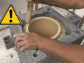 Ręce montują ceramiczny czopuch w konstrukcji z pustaków. Ostrzeżenie przed pracami budowlanymi.