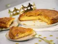 Une galette de farine dorée, prête à être dégustée, avec une fève cachée dans une part. Une couronne dorée trône à côté, promesse de fête.
