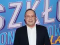 Uśmiechnięty mężczyzna w okularach na tle napisu "SZKŁO KONTAKTOWE OBSADA".