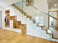 Schickes **schmales Reihenhaus einrichten**: Stauraumwunder unter der Treppe mit Garderobe, Regalen und Schubladen. Moderne Glasbrüstung.