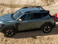 Zielony Dacia pickup z otwartą klapą bagażnika i czerwoną kanistrem na piasku.
