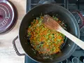 Würfel aus Karotten, Sellerie und Zwiebeln werden in einem Topf für ein soffritto rezept angedünstet.