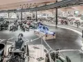 Wnętrze muzeum motocykli pełne zabytkowych maszyn, w tym motocykli z wózkami bocznymi i klasycznych samochodów.