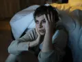 Zrezygnowana kobieta siedzi na podłodze obok łóżka, trzymając się za głowę. Wszystko mnie denerwuje w partnerze, nawet jego oddech.