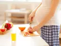 Schwanger, die Grapefruit für einen gesunden Snack schneidet. Nebenan liegen Paprika und ein Glas Saft.