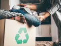 Pudełko z ubraniami i symbolem recyklingu. Wiesz, gdzie można oddać ubrania za darmo?
