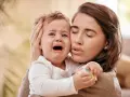 Zmartwiona mama tuli płaczące dziecko. Czy to mamoza?