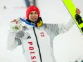 Kacper Tomasiak, skoczek narciarski, z dumą prezentuje medal i narty.