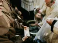 During a holy Thursday Catholic homily, a priest washes the feet of a man in a basin, symbolizing Christ's humility.