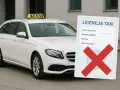 Biała taksówka z tabliczką "TAXI" i dokumentem "LICENCJA TAXI" z przekreślonym krzyżykiem. Kod zawodu taksówkarz.