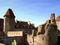 Potężne zamki nad morzem bałtyckim, w tym ruiny i zachowane budowle z cegły, pod błękitnym niebem.