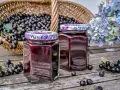 Zwei Gläser mit Aronia-Marmelade, bereit zum Verarbeiten. Ein Korb voller Aronia-Beeren steht im Hintergrund.