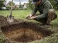 Mężczyzna bada ziemię po wykonaniu odwiertów geotechnicznych. Widać wykop i łopatę.