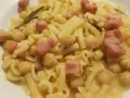 Piatto di pasta e ceci in scatola, con cubetti di pancetta e un rametto di rosmarino.