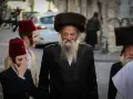 Men in traditional attire, including fur hats and red fez hats, walk together, perhaps celebrating the Purim meaning of joy and community.