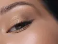 Maquillage paupière tombante : ombre dorée scintillante, trait d'eye-liner fin et cils longs pour un regard sublimé.
