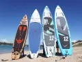 Vier Stand Up Paddles am Strand. Die Boards zeigen verschiedene Designs und Größen, die die Vor- und Nachteile von Stand up paddling beeinflussen können.