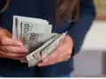 Dłonie trzymające plik polskich banknotów 100 zł. Zastanawiasz się, urlop wychowawczy ile płatny?