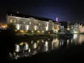 Nocna panorama miasta nad rzeką, z oświetlonymi kamienicami i odbiciami świateł w wodzie. To prawdziwa opolska wenecja.