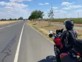 Motociclista su strada panoramica Foresta Nera, con campi di mais e pale eoliche all'orizzonte.