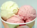 Drei Kugeln Eis in einem Becher: eine hellgelbe und zwei rosafarbene. Verschiedene eis arten für süße Momente.