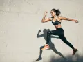 Kobieta w sportowym stroju biegnie, wykonując trening tlenowy i beztlenowy. Jej cień podkreśla dynamikę ruchu.