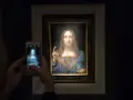 Persona toma foto a Salvator Mundi, el cuadro más caro del mundo, con su móvil.