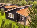 Czarny bungalow z pomarańczowym dachem, otoczony zielenią. To idealne miejsce na wypoczynek, co to znaczy bungalow?