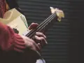 Dłonie grają na gitarze, ludowy instrument szarpany z rysunkiem kaktusa.