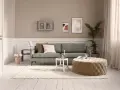Gemütliches kleines Wohnzimmer einrichten mit grauem Sofa, beigem Hocker, weißem Teppich und Wanddeko.