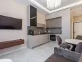 Un moderno open space lungo e stretto con cucina a vista, zona TV e tavolo da pranzo.