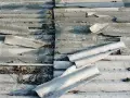 Zniszczone eternitowe pokrycie dachowe, z odpadającymi fragmentami i liśćmi. Kara za eternit jest nieunikniona.
