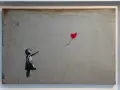 Dziewczynka sięga po czerwony balon w kształcie serca. To słynne dzieło Banksy'ego, artysty znanego z prowokacyjnych prac.