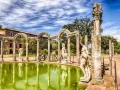 Starożytne ruiny i rzeźby w Villa d'Este odbijają się w zielonym stawie.
