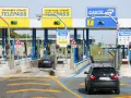 Casello autostradale con auto in coda. Segnaletica per Telepass e carte di credito. Possibile problema di mancato pagamento Telepass per un veicolo.