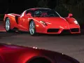 Czerwone Ferrari Enzo zaparkowane nocą na drodze, z innym czerwonym samochodem w tle.