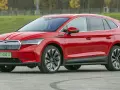 Czerwona Skoda Enyaq na tle zieleni, z tablicą rejestracyjną PY 00017. Ten elektryczny SUV oferuje imponujący zasięg.