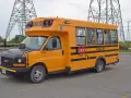 Żółty autobus szkolny GMC z napisem "SHARP" i znakiem STOP. Zastanawiasz się, ile kosztuje autobus?