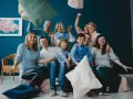 Wesoła rodzina patchworkowa rzuca poduszkami, śmiejąc się i ciesząc wspólnym czasem.