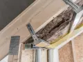 Konstrukcja poddasza z wełną mineralną i metalowymi wieszakami kotwowymi, gotowa do montażu płyt gipsowo-kartonowych.
