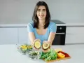 Uśmiechnięta kobieta prezentuje awokado, składnik wielu diet, w tym keto. Jej opinie o keto diecie są pozytywne.