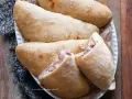 Calzoni al forno dorati e fragranti, ripieni di prosciutto e formaggio filante, pronti per essere gustati.