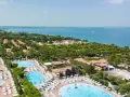 Widok z lotu ptaka na camping Piani di Clodia z basenami, domkami i jeziorem w tle.