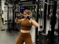 Kvinna utför stående rodd med kabelmaskin. Hon fokuserar på träningen i gymmet.