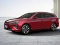 Czerwony MG5 Electric, kombi, stoi na betonowym placu z widokiem na morze.