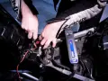 Mani che collegano un caricabatterie Exide a una batteria di moto. La batteria non tiene la carica, quindi si prova a ricaricarla.