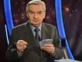 Starszy mężczyzna w garniturze trzyma okulary i karty z napisem "jeden z dziesięciu kiedy".