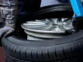 Mechanik w rękawiczce przygotowuje felgę do wymiany opon. Dowiedz się, ile kosztuje wymiana opon.