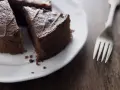 Una fetta di torta al cioccolato su un piatto bianco, con una forchetta accanto. Un'opzione deliziosa per chi cerca dolci senza zucchero.